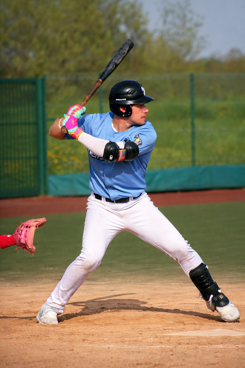 baseball player mid swing wearing colorful batting gloves hc glove co on field showing performance grip control and premium gear during game action